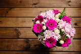 A large beautiful bouquet of chrysanthemums, gerberas, roses and ferns in pink and purple colors wrapped in brown craft paper on a wooden background. Postcard for the holiday. Close-up
