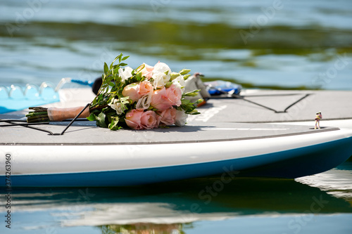 A beautiful bridal bouquet of delicate roses and other fresh flowers lying on the SUP board.