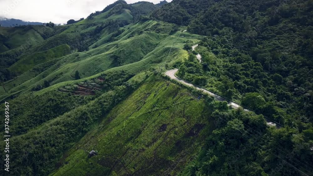 Aerial view of countryside road passing through the serene lush greenery and foliage tropical rain forest mountain landscape on the Doi Phuka Mountain reserved national park the northern Thailand Aerial view of countryside road passing through the serene lush greenery and foliage tropical rain forest mountain landscape on the Doi Phuka Mountain reserved national park the northern Thailand