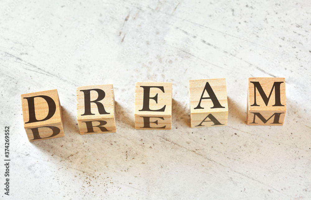 Five wooden cubes with letter DREAM (acronym for Dedication Responsibility Education Attitude Motivation) on white stone like board, view from above Five wooden cubes with letter DREAM (acronym for Dedication Responsibility Education Attitude Motivation) on white stone like board, view from above