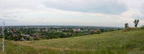 Wonderful rural landscape. View from a hill to a valley with a village and a city on a blue sky with clouds background