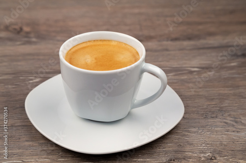 A white cup with coffee on a wooden background