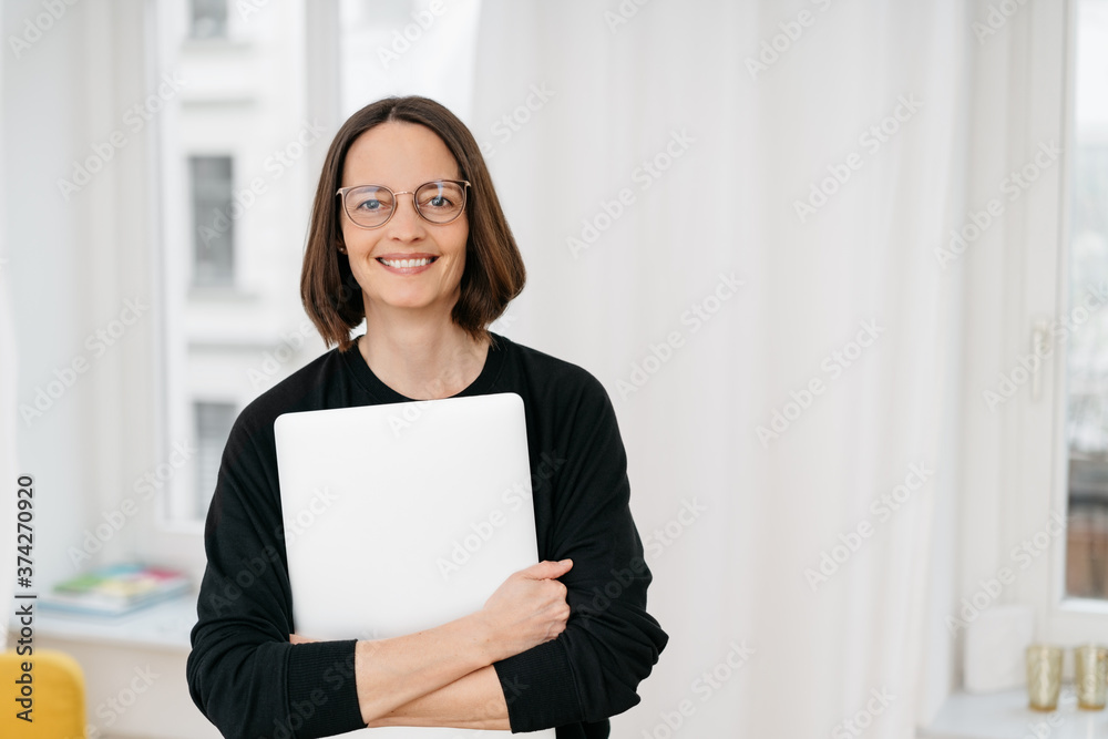 Smiling woman hugging a laptop to her chest Smiling woman hugging a laptop to her chest