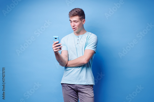 Youth and technology. Young handsome man using smartphone against blue background.