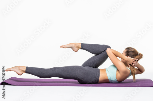 Young woman exercising and doing a crunch to work her abs isolated white background