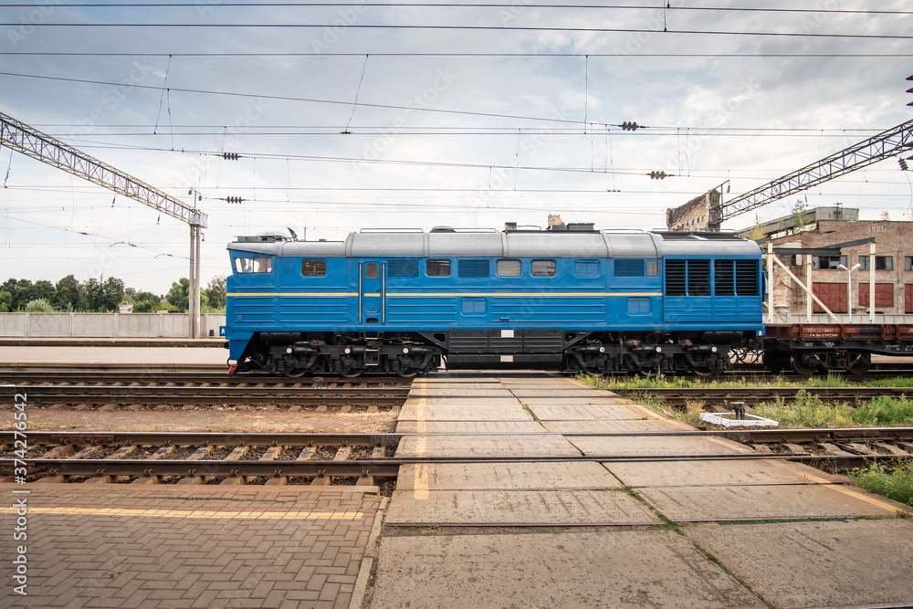 Fototapeta premium Blue shunting locomotive rides at the train station.