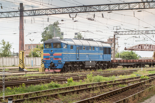 Blue shunting locomotive rides through industrial area. © Dmytro