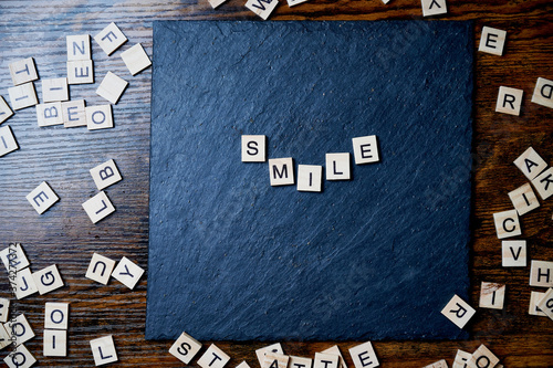 smile message written with wooden letters on slate stone