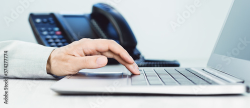 business and communications. Female hand and voip phone in the office, close up of hand.. Application. laptop on desk. IP telephony, Cold calling. Audit or accounting. Induction banner