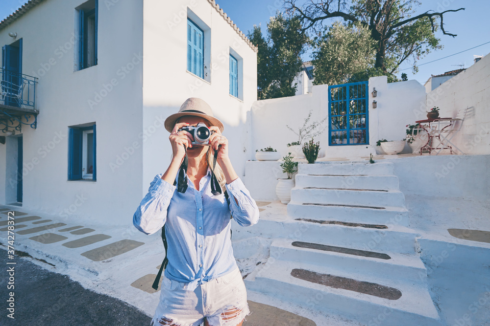 Tourism and technology. Happy young woman taking photo of old town. Traveling by Greece.