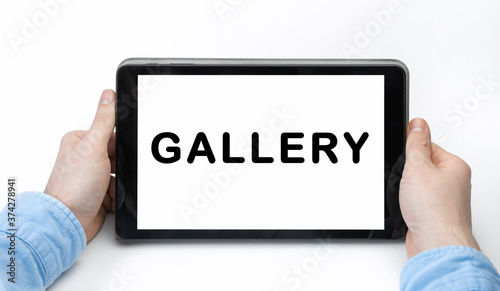 Male hands holding tablet pc with text GALLERY on white background © AstiMak