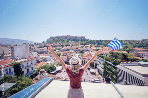 Enjoying vacation in Greece. Young traveling woman with national greek flag enjoying view of Athens city and Acropolis.