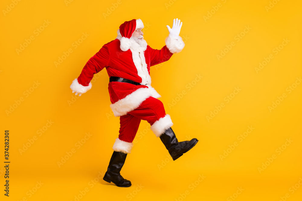 Full length body size profile side view of his he nice funny thick elderly white-haired Santa St Nicholas going having fun making step sale isolated bright vivid shine vibrant yellow color background Full length body size profile side view of his he nice funny thick elderly white-haired Santa St Nicholas going having fun making step sale isolated bright vivid shine vibrant yellow color background