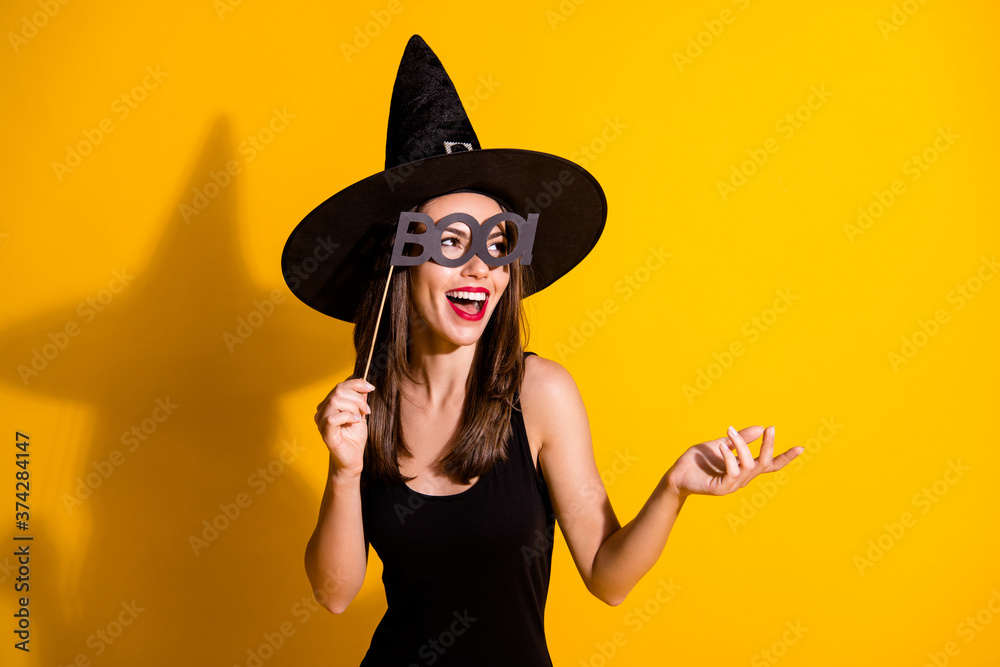 Close-up portrait of her she nice attractive pretty cheerful cheery lady wizard holding in hand glasses boo word festive day having fun isolated bright vivid shine vibrant yellow color background Close-up portrait of her she nice attractive pretty cheerful cheery lady wizard holding in hand glasses boo word festive day having fun isolated bright vivid shine vibrant yellow color background