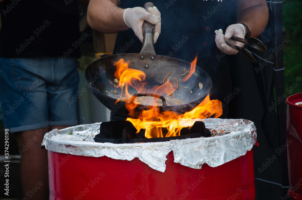 Fire frying pan street food. Chef fire cooking nature.