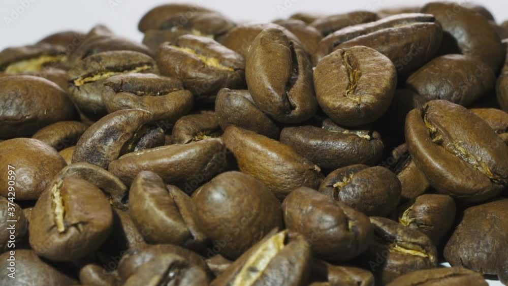 Dark Coffee beans rotating. Close up of roasted coffee beans on white background. Shallow depth of field Dark Coffee beans rotating. Close up of roasted coffee beans on white background. Shallow depth of field