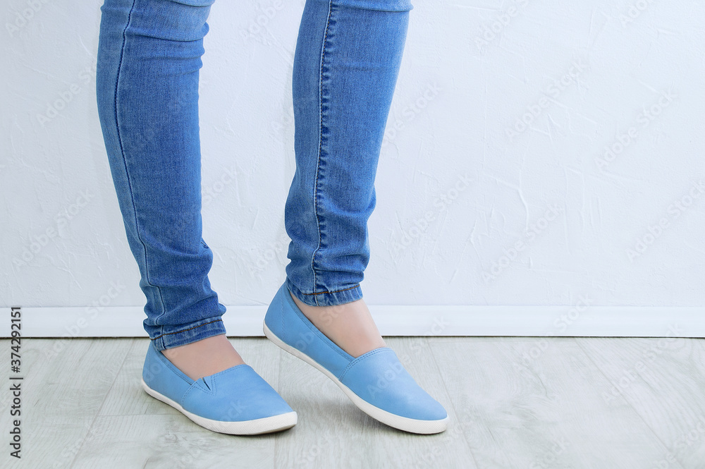 Clothes and footwear. Legs of caucasian woman in skinny jeans and blue shoes close up. Clothes and footwear. Legs of caucasian woman in skinny jeans and blue shoes close up.