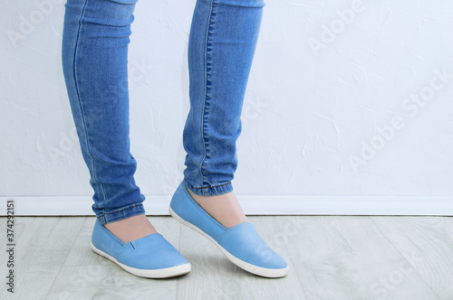 Clothes and footwear. Legs of caucasian woman in skinny jeans and blue shoes close up.