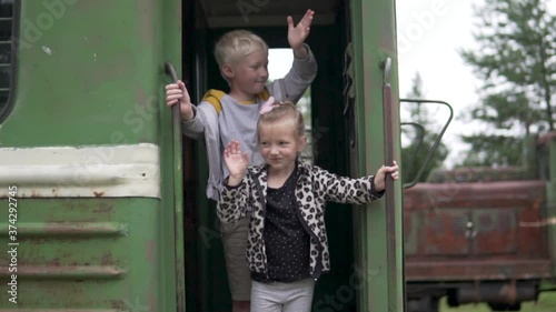 Children wave goodbye from the last carriage of the departing train.