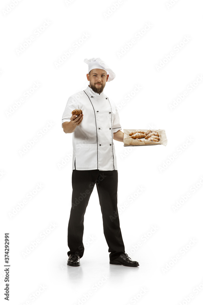 Cooker, chef, baker in uniform isolated on white studio background with croissants. Young man, restaurant cooker's portrait. Business, foor, professional occupation, emotions concept. Copyspace for ad Cooker, chef, baker in uniform isolated on white studio background with croissants. Young man, restaurant cooker's portrait. Business, foor, professional occupation, emotions concept. Copyspace for ad