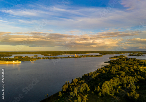 Fototapeta Naklejka Na Ścianę i Meble -  panoramic view of the lake with many islands on one of them there is an ancient temple made of wood at sunset filmed from a drone