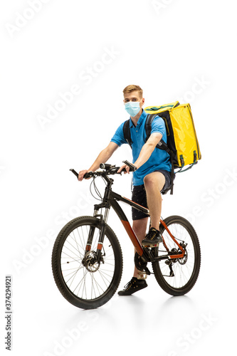Deliveryman in face mask with bicycle isolated on white studio background. Contacless service during quarantine. Man delivers food during isolation. Safety. Professional occupation. Copyspace for ad.