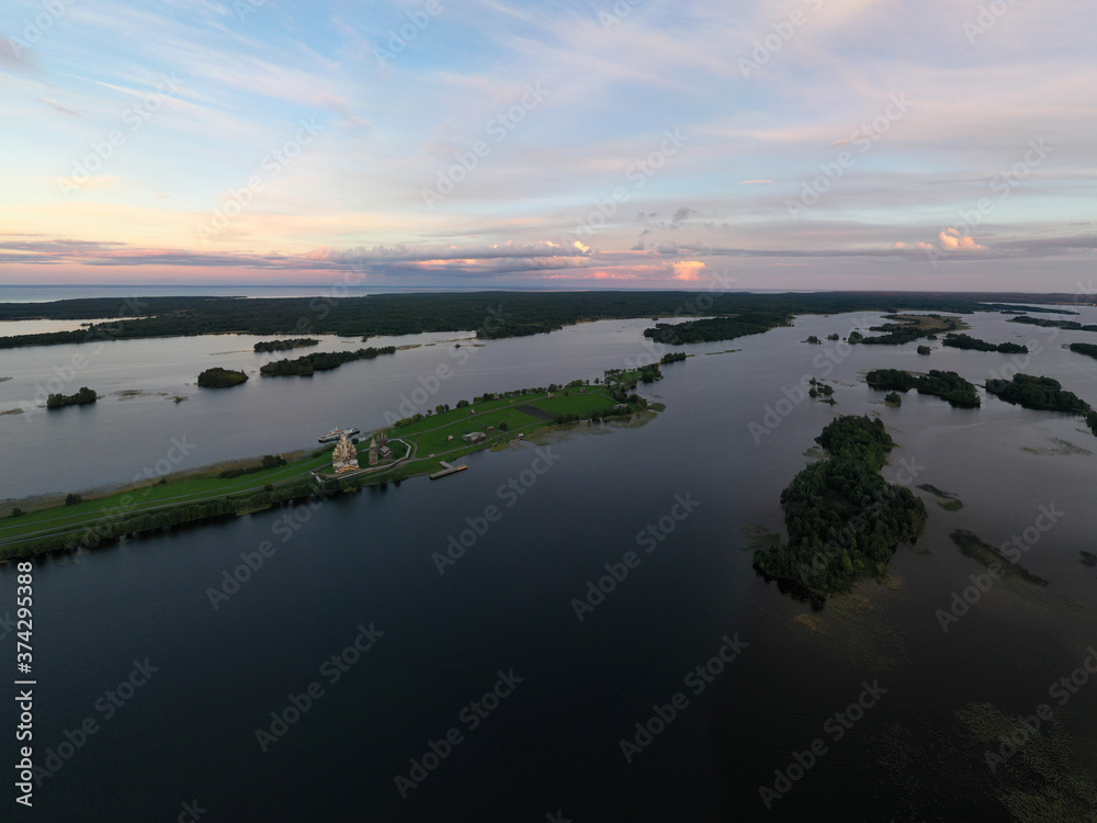 Fototapeta premium panoramic view of the lake with many islands on one of them there is an ancient temple made of wood at sunset filmed from a drone