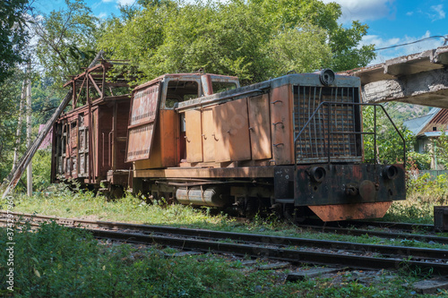 Old diesel locomotive with broken wooden cargo wagon on railway