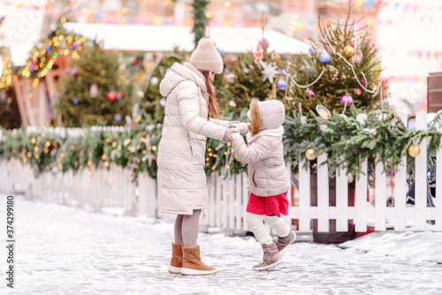 Cheerful family, mother and little girl having fun on Christmas market.