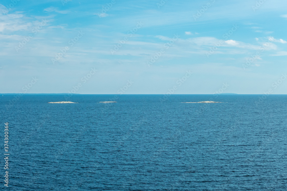 Three little white islands on blue background of water and cloudy sky on Ladoga lake in Karelia Three little white islands on blue background of water and cloudy sky on Ladoga lake in Karelia