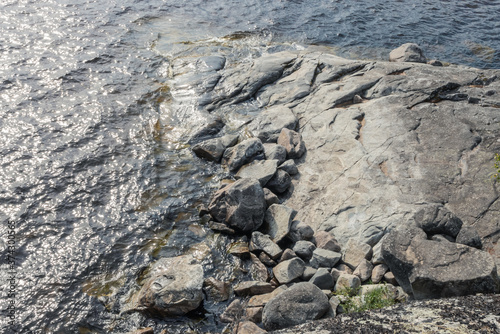Top view on textured grey rocks on a shore surrounded by water of Ladoga lake in Karelia © ilyablinov