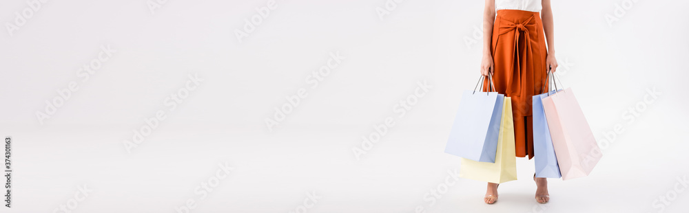 cropped view of elegant woman with shopping bags on white, panoramic shot