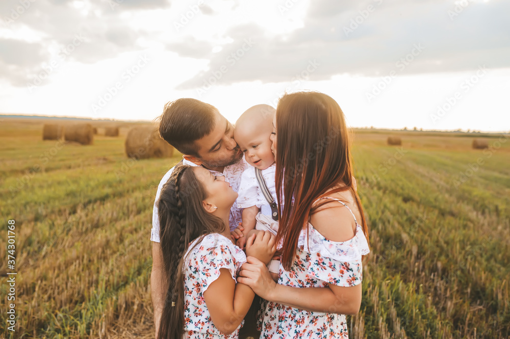 Dad, mom hugging and kissing of their children in wheat field on sunset. Dad, mom hugging and kissing of their children in wheat field on sunset.