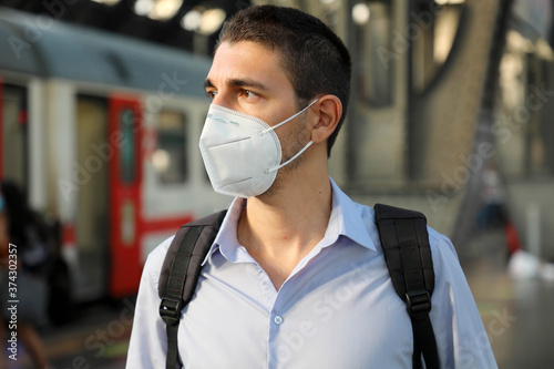 Portrait of man waiting train with KN95 FFP2 protective mask at train station photo