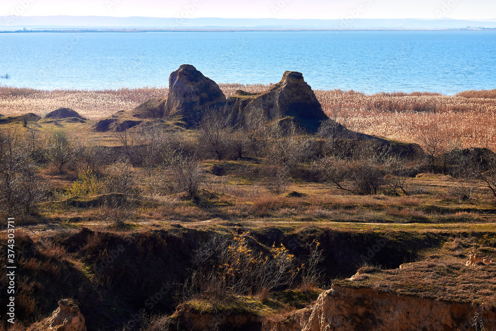 Clay rocks, a cliff on the shore of the lake. The hilly coast at sunny autumn day.