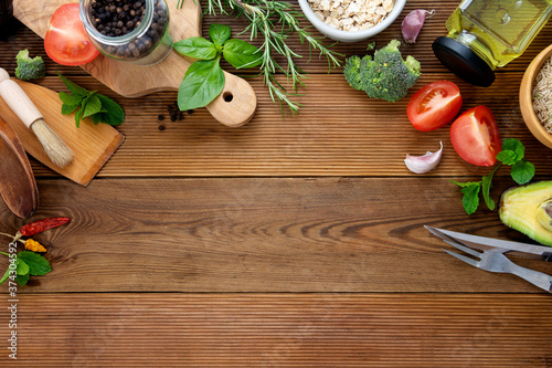 Food frame, cooking mockup. Tomatoes, herbs, oil, cutting board, broccoli, pepper, kitchen utensils. Wooden background, copy space. photo