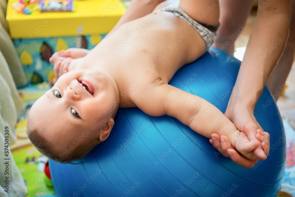Naklejka premium Toddler training with gymnastic ball with mother at home.