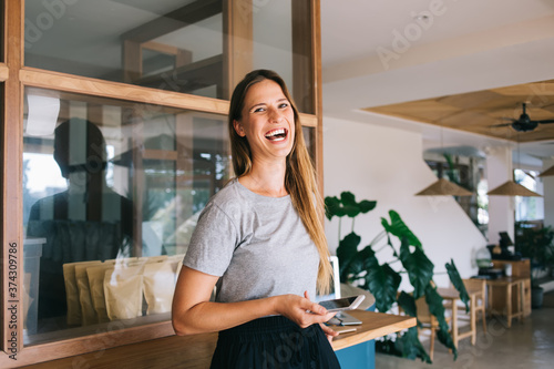 Portrait of cheerful happy caucasian female in casual wear laughing at funny message on smartphone, carefree expressive woman looking at camera having fun on leisure satisfied with 4G connection
