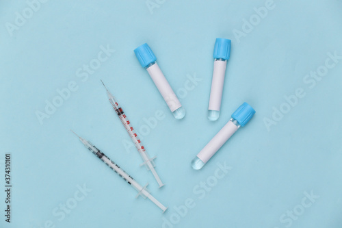 Medical test tubes with syringes on blue background. Vaccination. Top view
