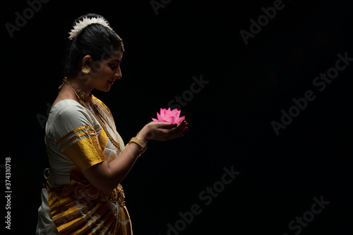 Mohiniattam artist smiling at a lotus flower in her hand
 photo