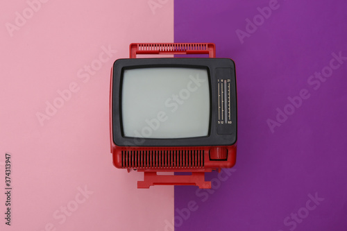 Red retro old mini tv set on purple piink background. Top view photo