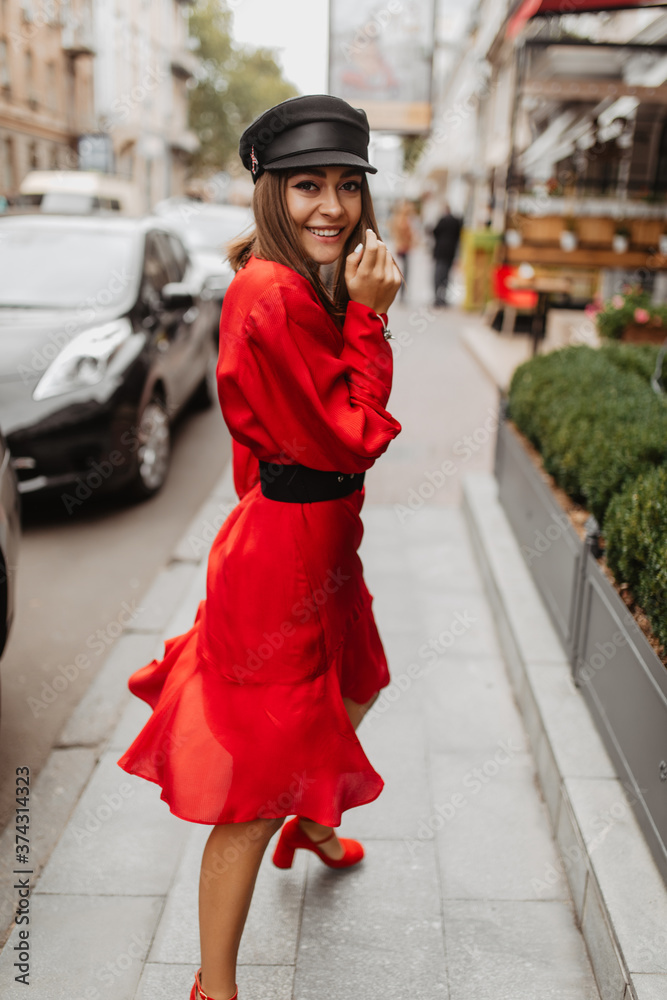 Street dancer model with thin waist poses for street photo. Lady in red dress highlighted elegant silhouette with belt