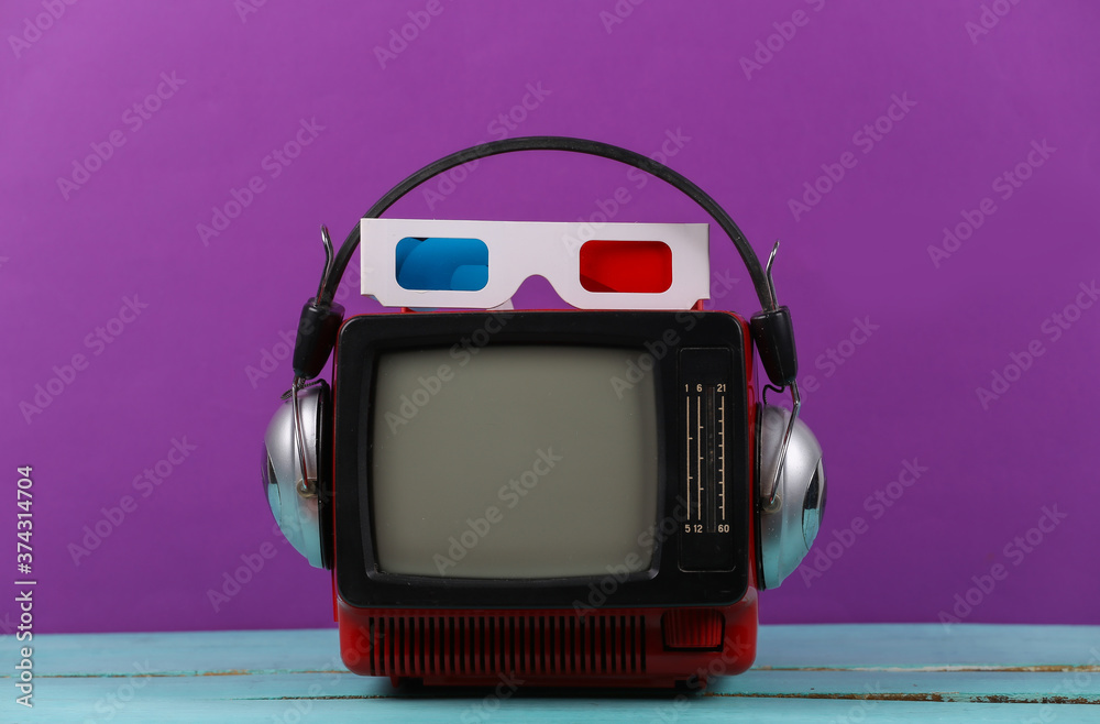 Red retro old portable mini tv set with headphones, 3d glasses on purple background. Attributes 80s, retro style