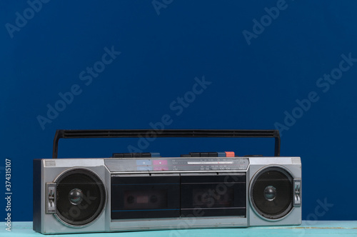 80s Retro outdated portable stereo radio cassette Recorder on classic blue Background.