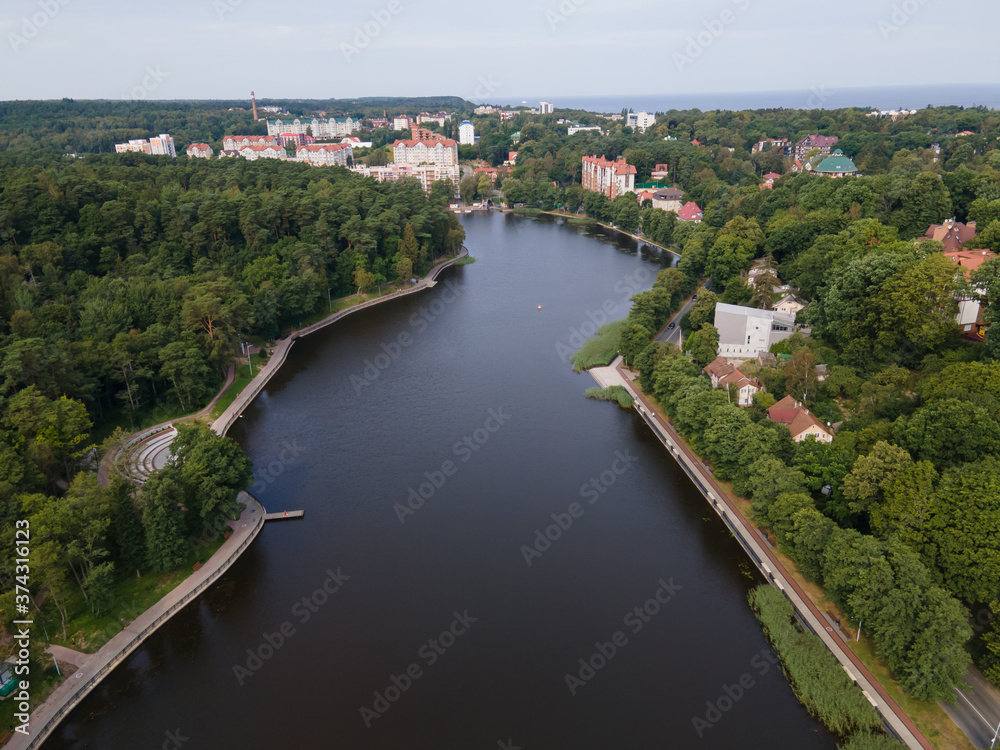 Drone view of quite lake in Svelogorsk in sunny day, forest around water