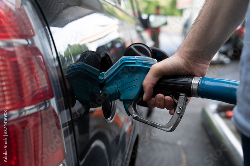 Male hand fills gasoline in a car with gas pump nozzle