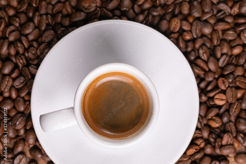 Fototapeta premium Mugful of coffee in white cup and saucer with coffee grains background