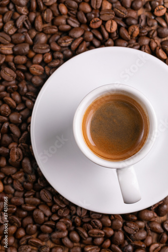 Mugful of coffee in white cup and saucer with coffee grains background