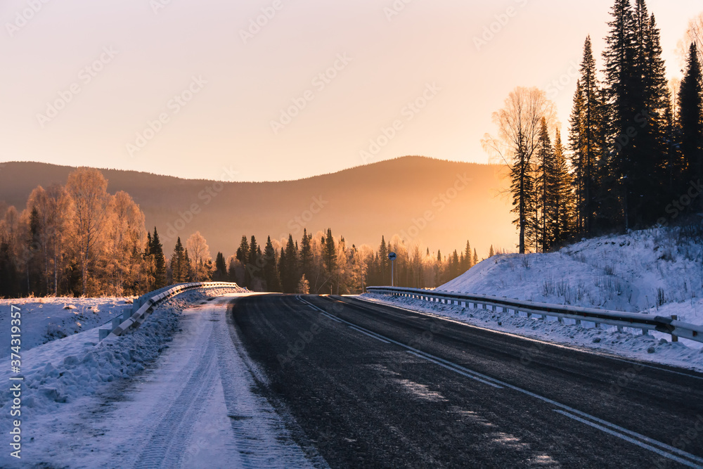 The road in the winter mountains in the background at sunrise
