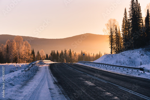 The road in the winter mountains in the background at sunrise 